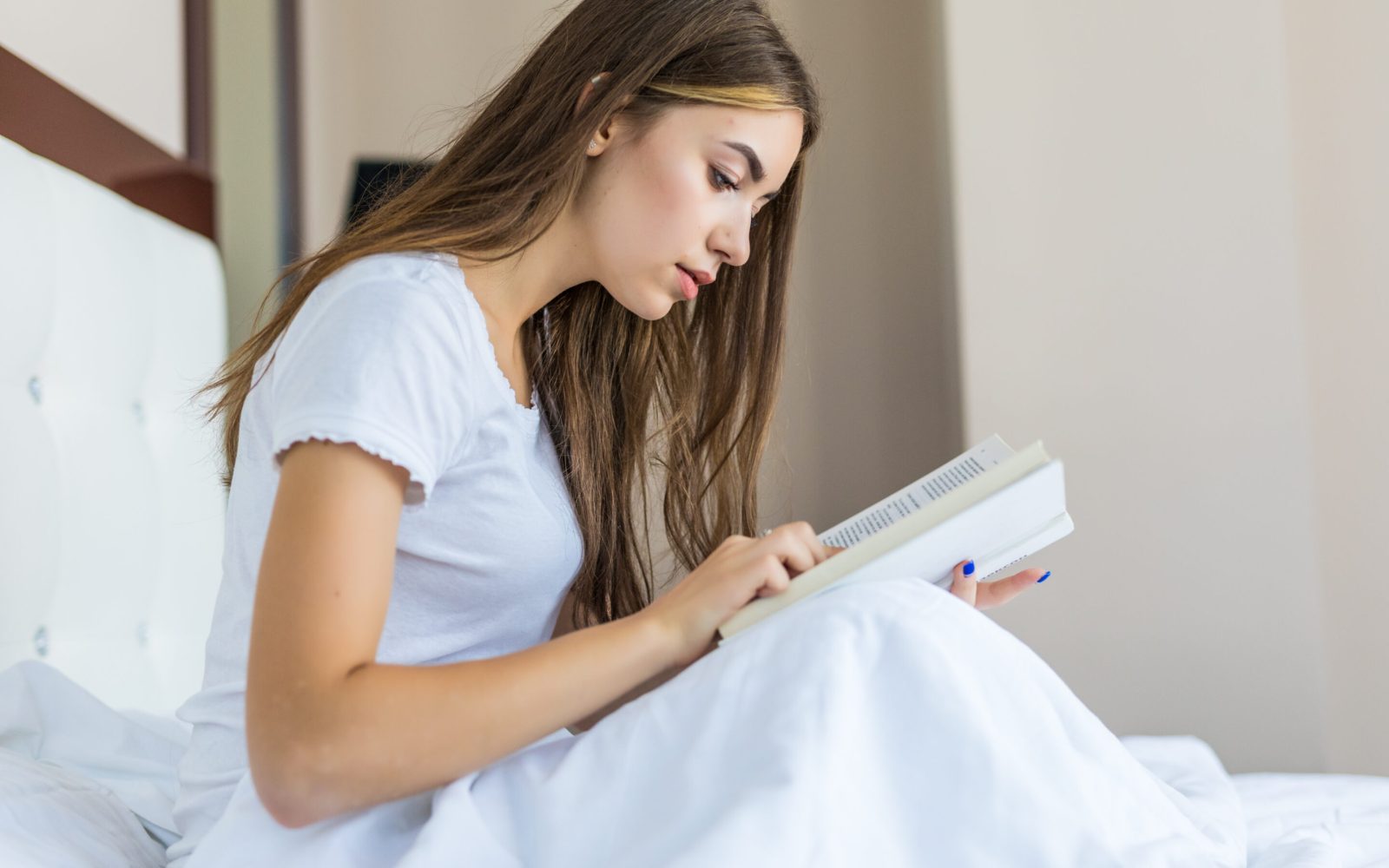 Happy young woman relaxing at home and reading a book