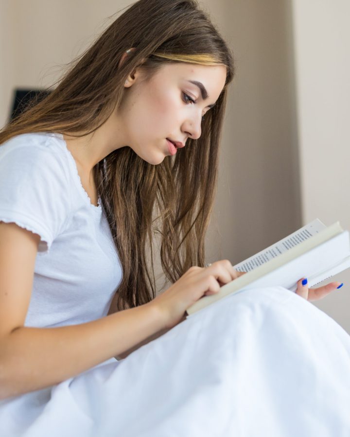Happy young woman relaxing at home and reading a book