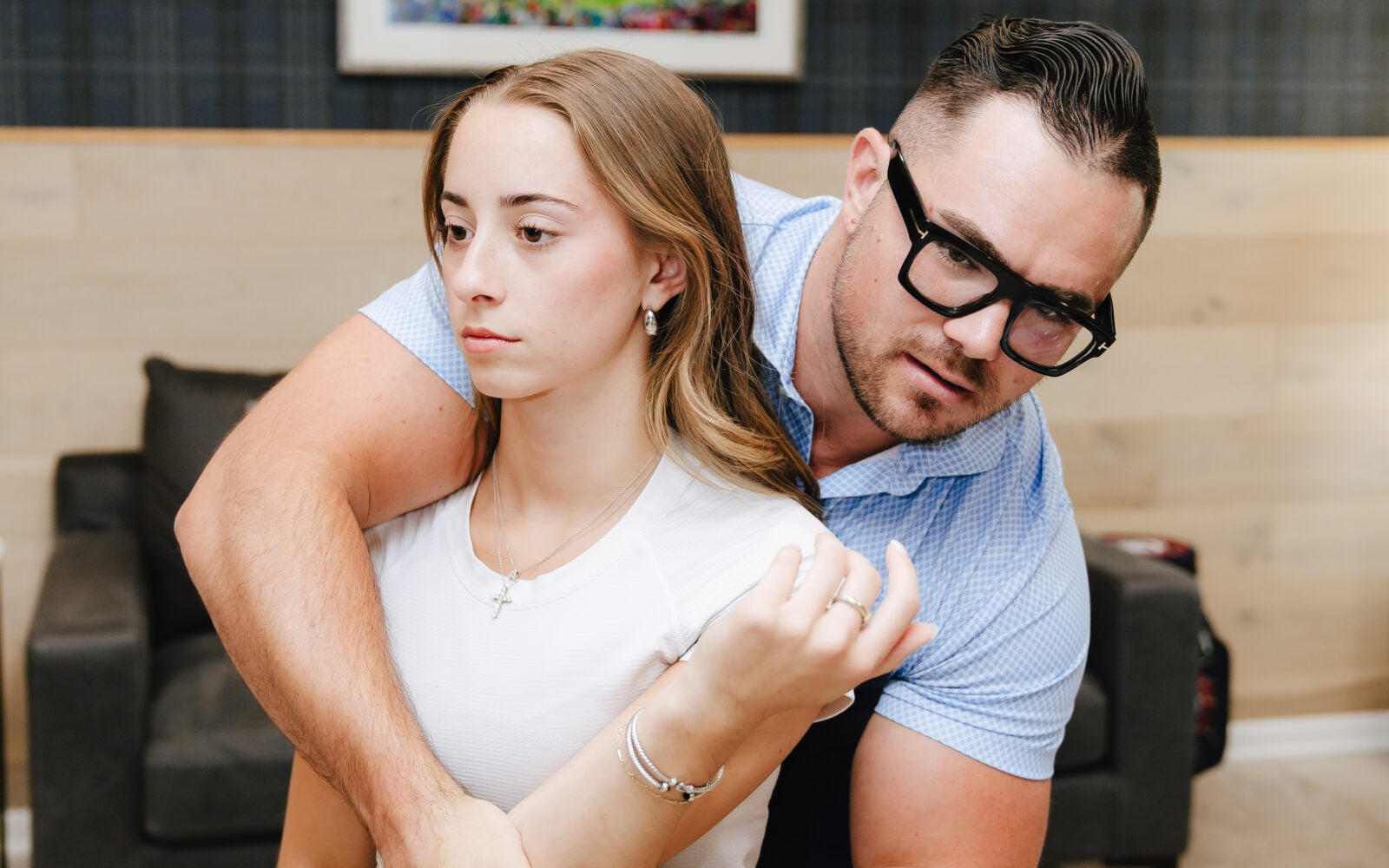 Chiropractor assessing a seated patient’s shoulder and arm mobility