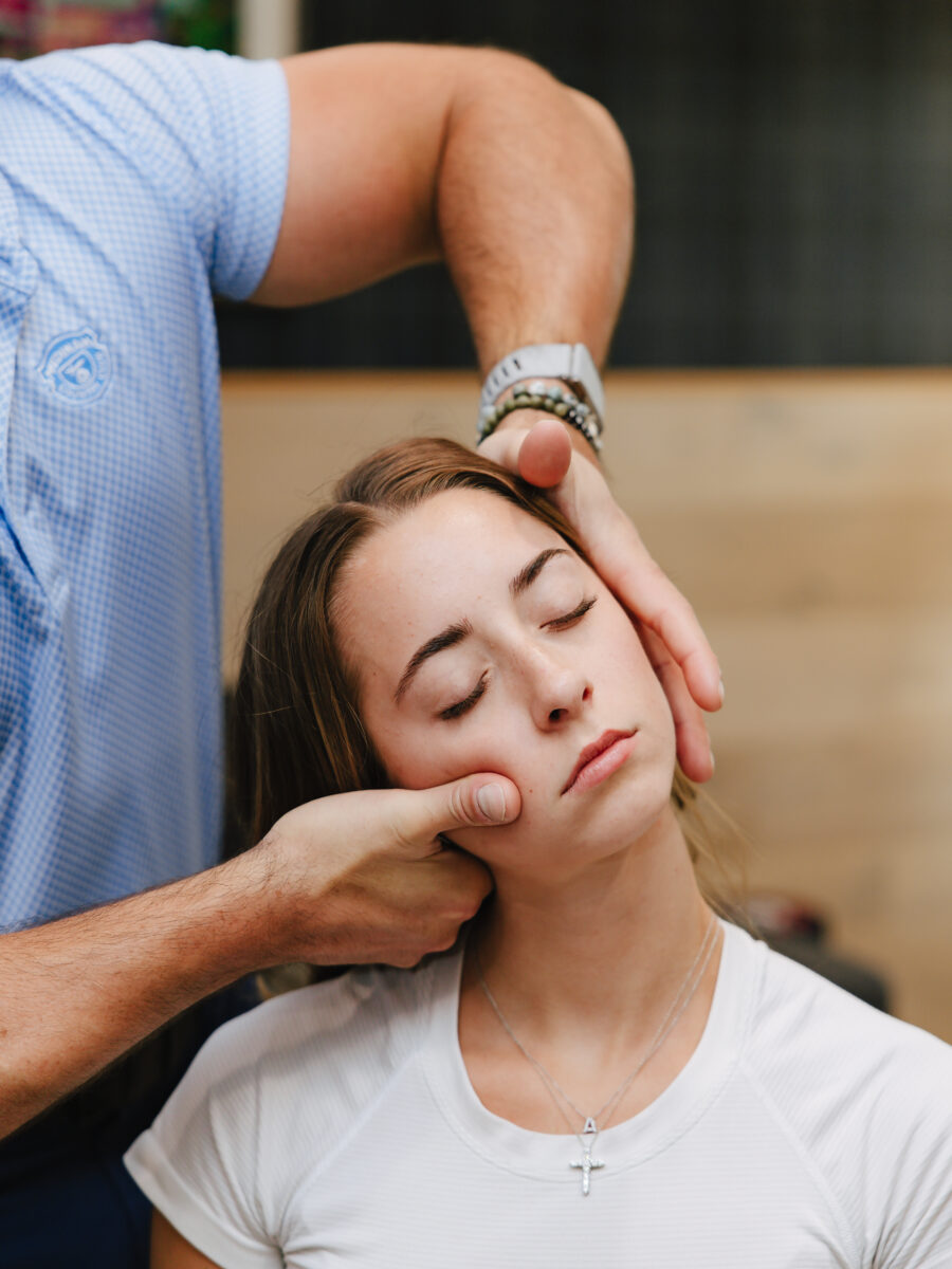 Chiropractor performing a gentle neck and jaw assessment on a patient at Forza Chiropractic