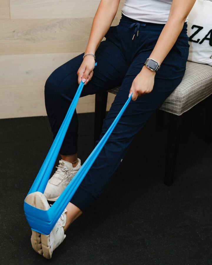 Guided resistance band leg exercise during rehab at Forza Chiropractic