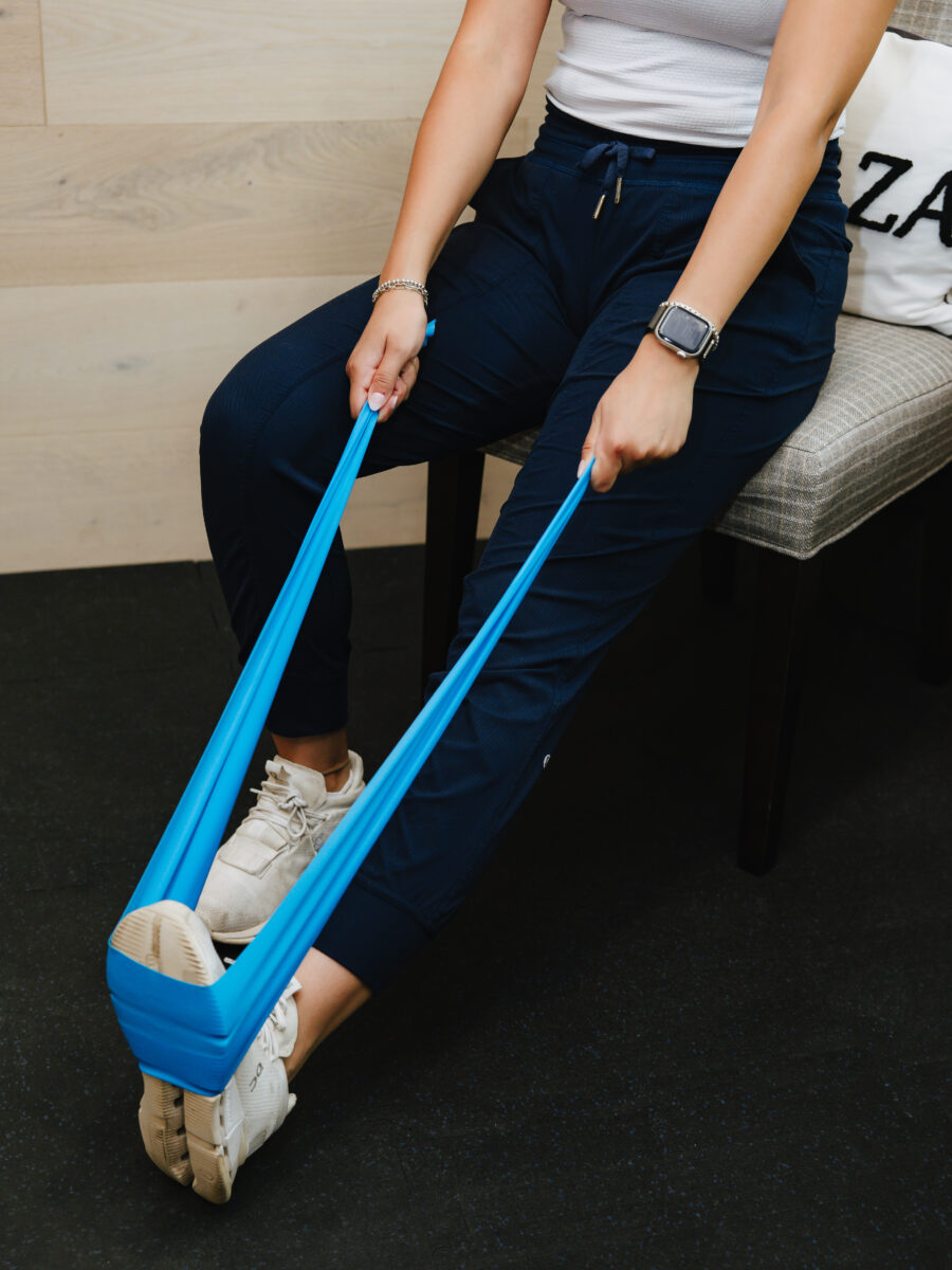Guided resistance band leg exercise during rehab at Forza Chiropractic