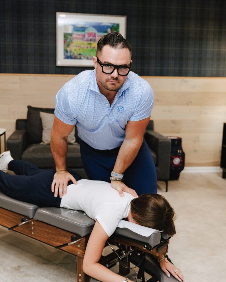 Chiropractor performing an upper back adjustment on a prone patient